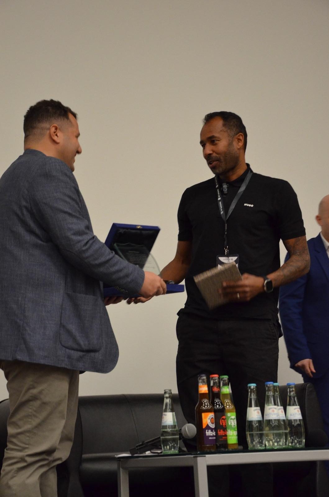 Award plaque handshake at conference