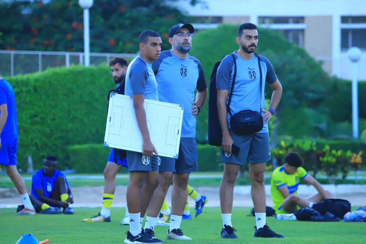 Coaching staff with tactical board on pitch